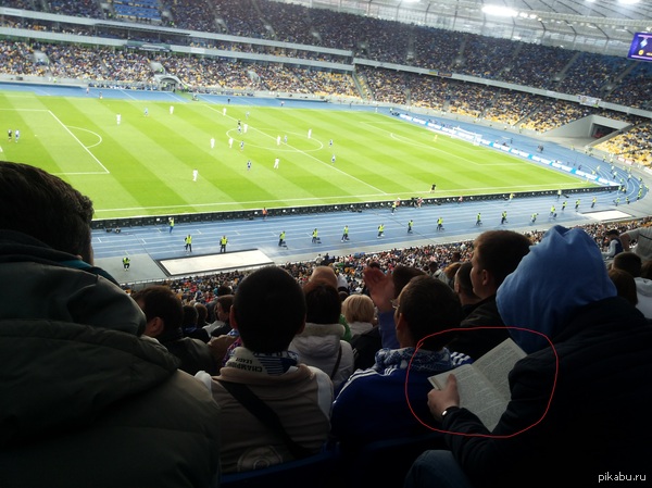 Просто парень, читающий книгу на футбольном матче.